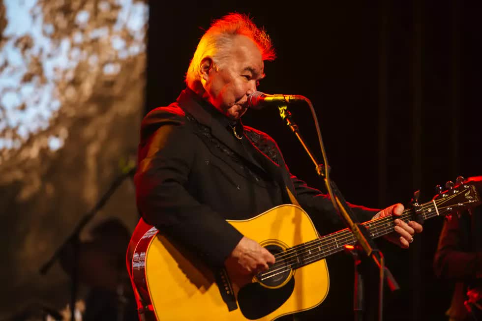 John Prine playing acoustic guitar on stage