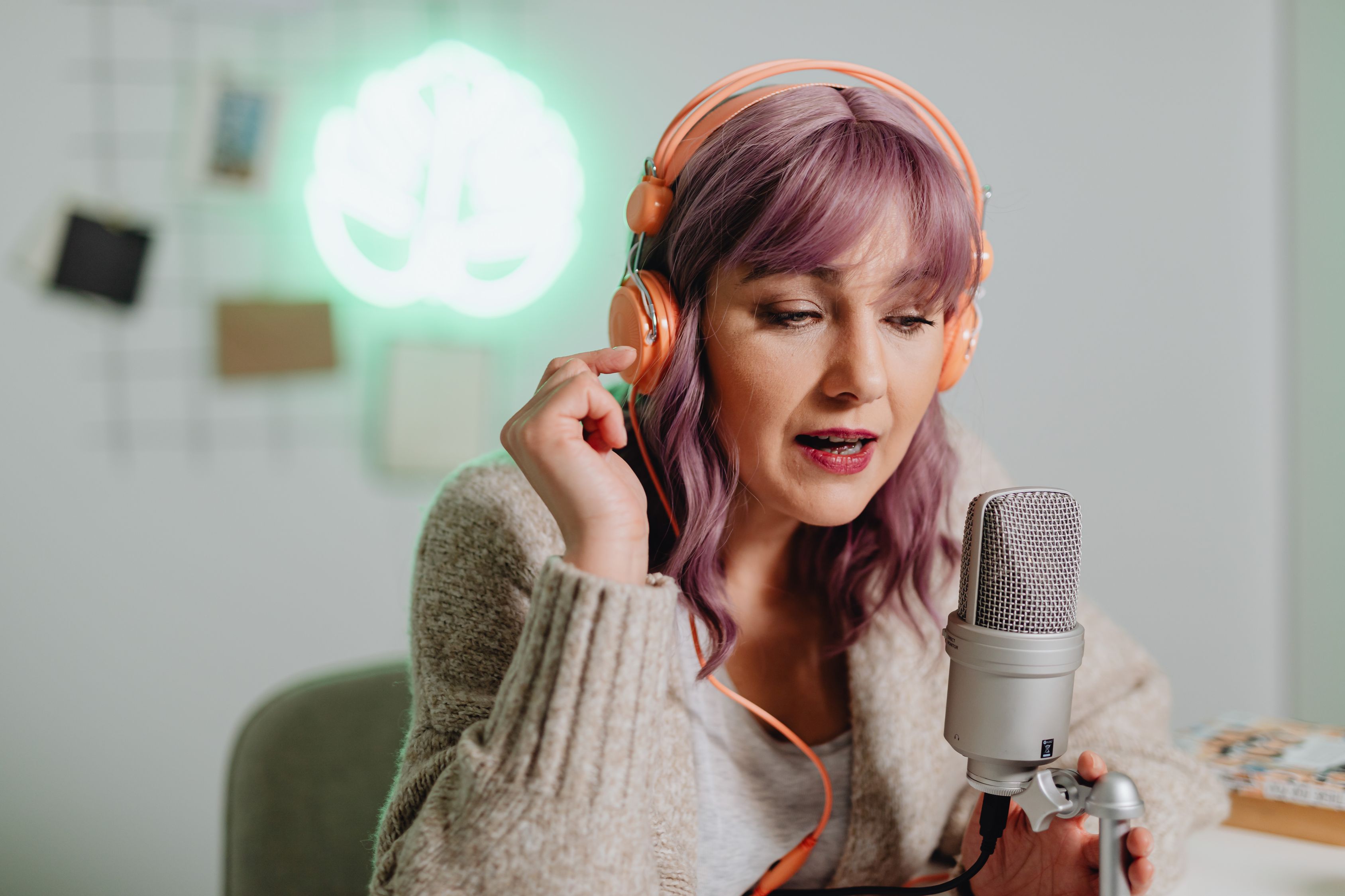 A woman recording a podcast episode in a bright studio, speaking into a professional microphone