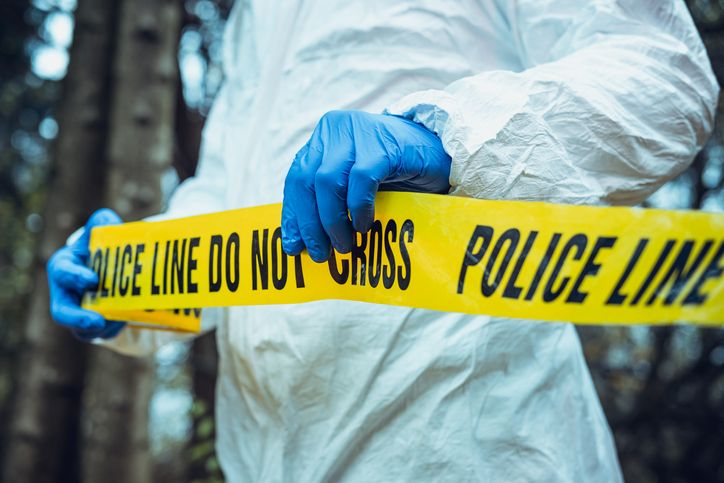 Crime scene tape stretched across an investigation site in daylight
