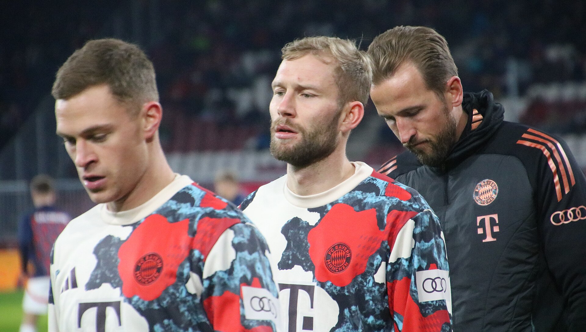 Harry Kane in a black Bayern Munich training top, head bowed, alongside Joshua Kimmich and Konrad Laimer