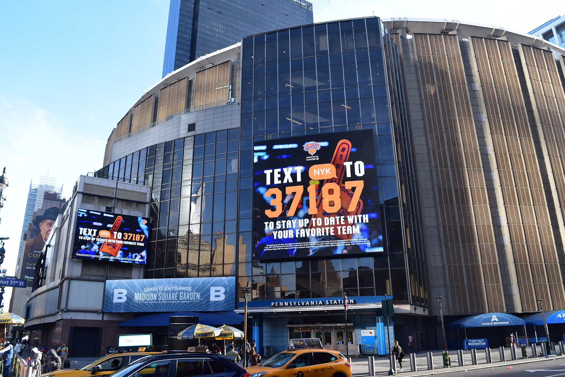 Madison Square Garden in New York in bright daylight, its glass facade carrying New York Knicks branding