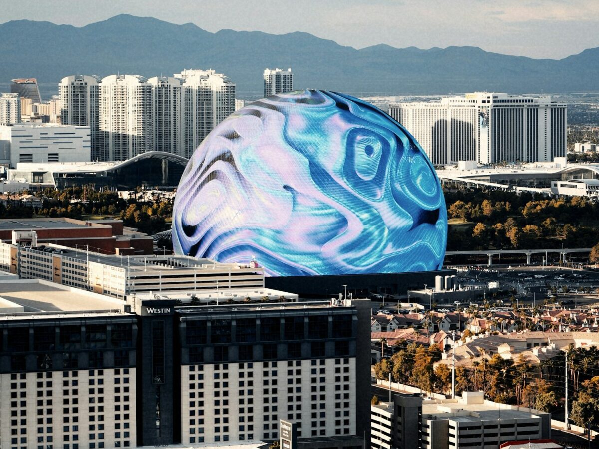 The Sphere in Las Vegas glowing with blue swirl visuals on its exterior display in daylight, with the city skyline behind it