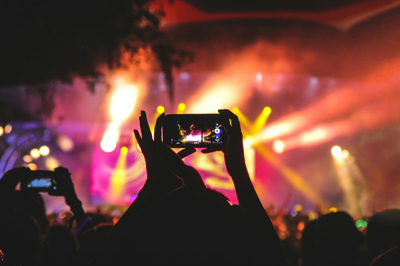 A bright concert stage with a performer silhouetted against warm lights