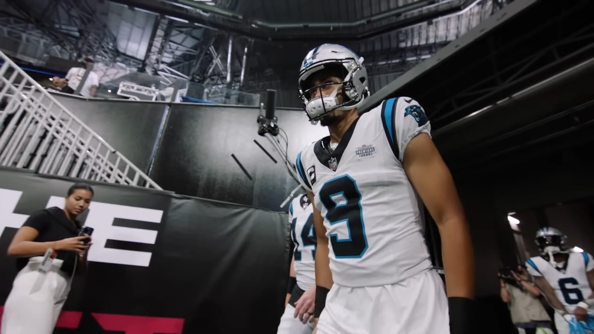 Carolina Panthers quarterback Bryce Young walking through the stadium tunnel in his white Panthers uniform