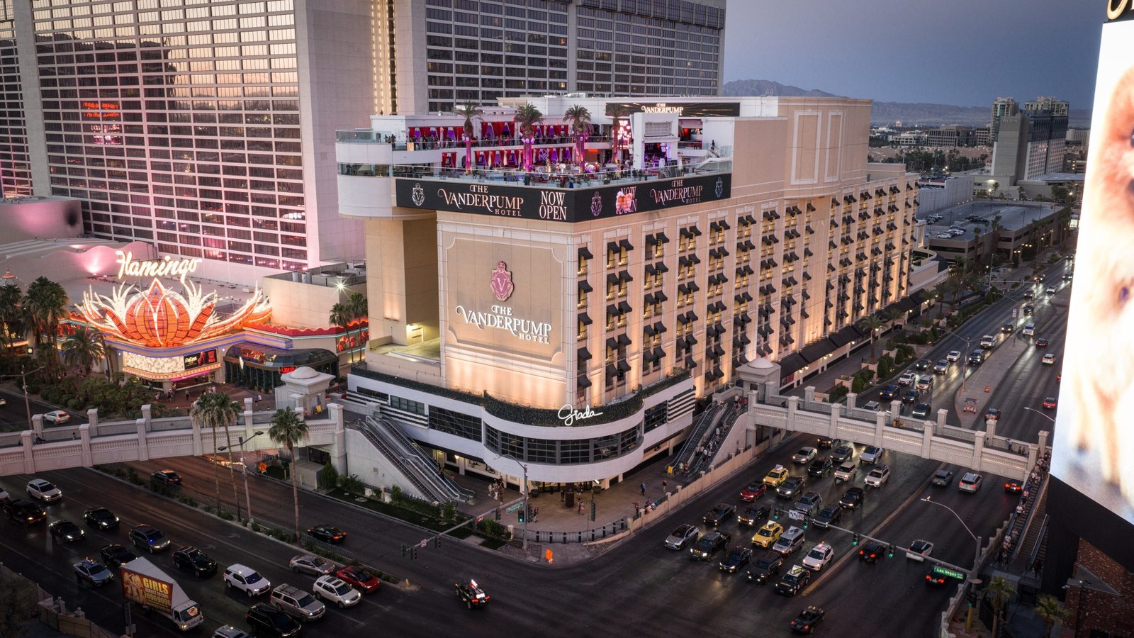 The Vanderpump Hotel lit up at dusk on the Las Vegas Strip with its Now Open banner beside the Flamingo