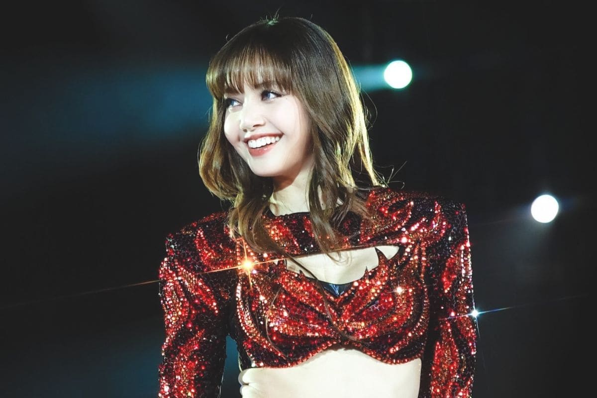 LISA smiling on stage in a sparkling red outfit during a live performance