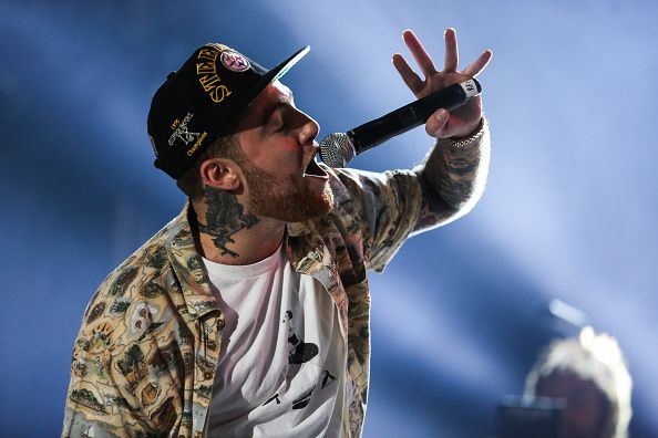 Mac Miller performing on stage, backlit in warm light