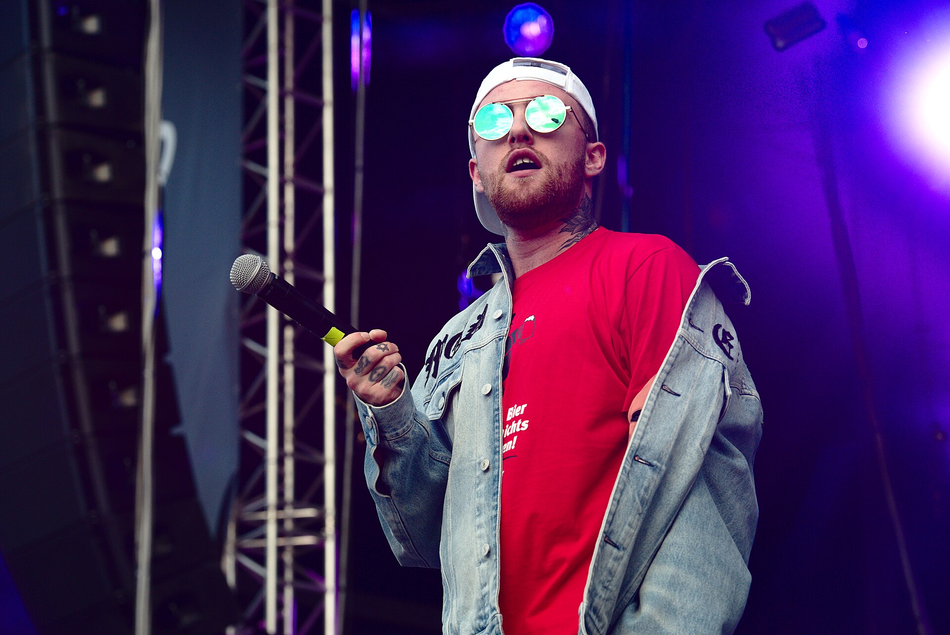 Mac Miller singing into a microphone during a live performance