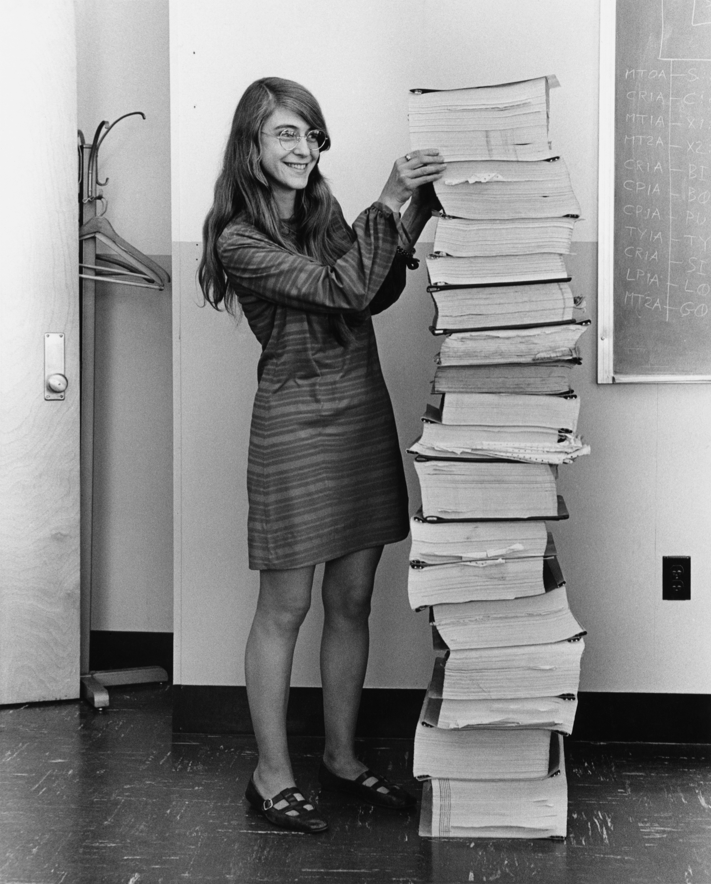 Margaret Hamilton standing beside the stack of Apollo guidance computer software listings she and her MIT team wrote, photographed in 1969