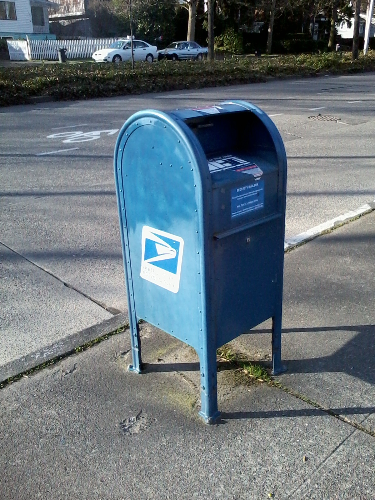 A blue U.S. Postal Service collection box in daylight