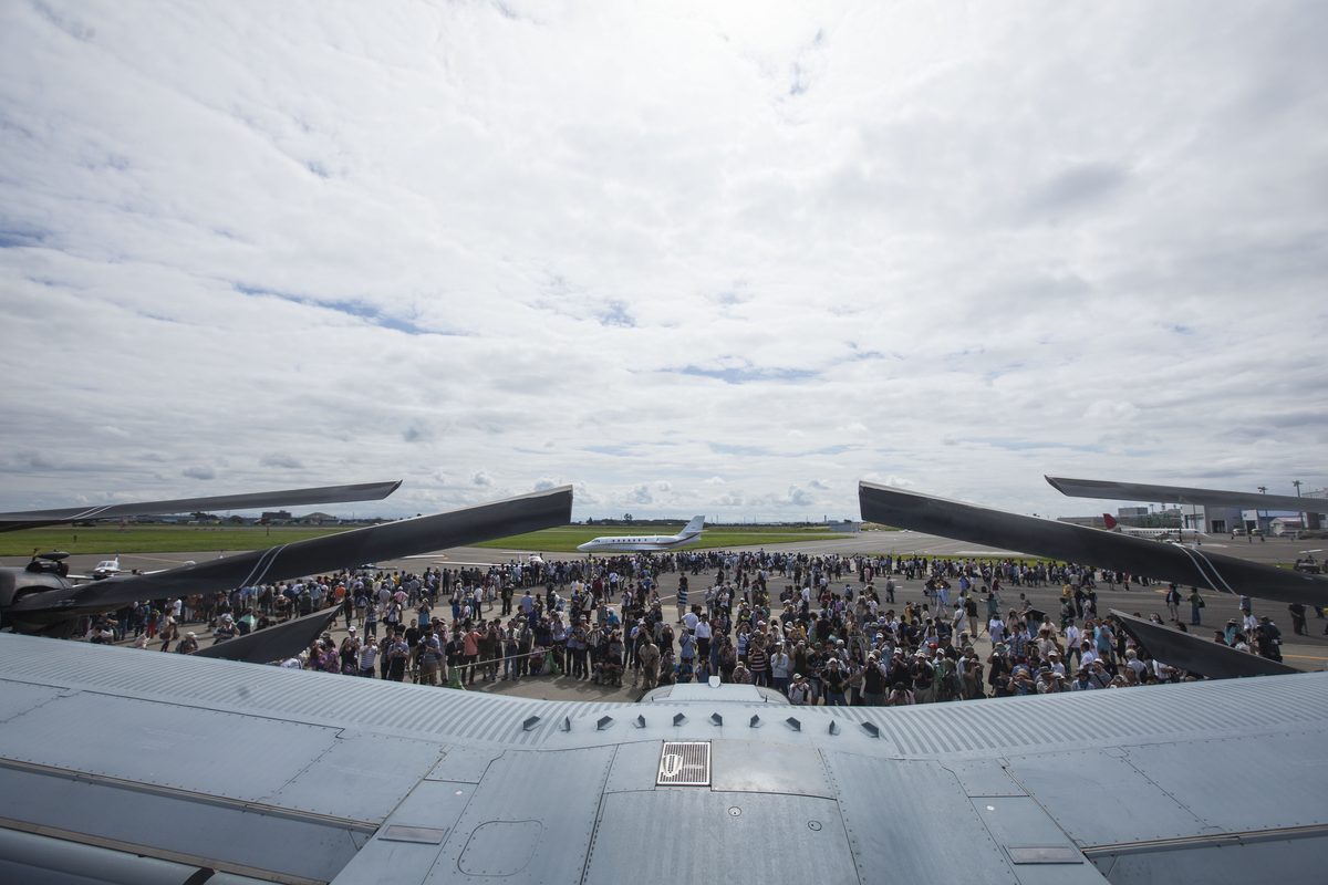 Onlookers walk beneath the rotor of an MV-22 Osprey at an air show