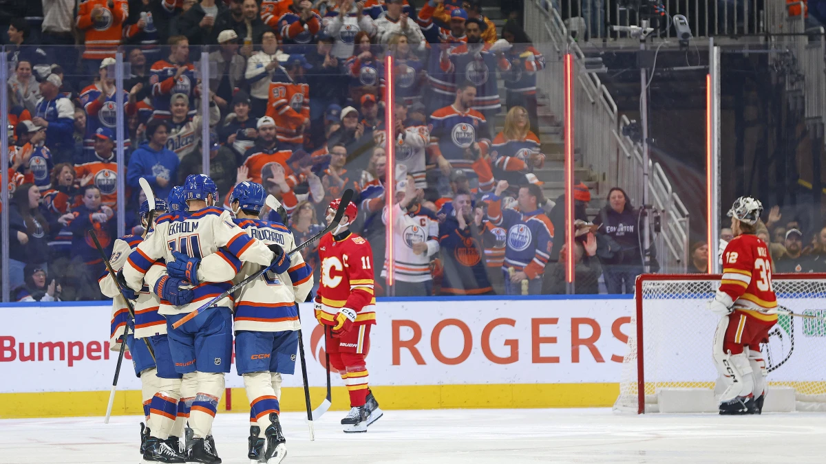 Mattias Ekholm is mobbed by Oilers teammates after scoring against Calgary, the goal light lit behind the net