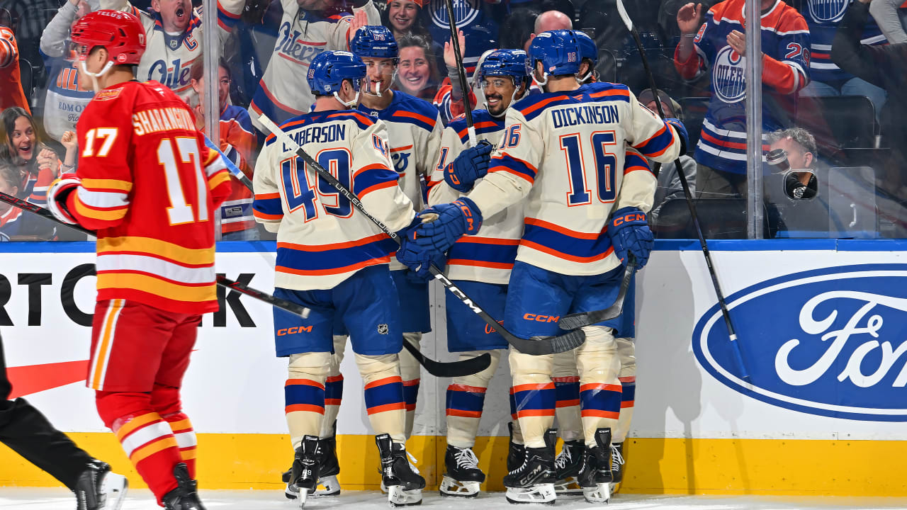 Oilers players celebrate a goal at the boards at Rogers Place as Calgary's Yegor Sharangovich skates away