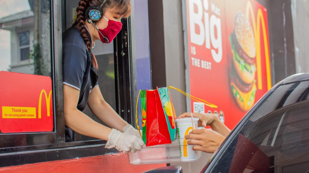 Cars in line at a McDonald's drive thru during the day.