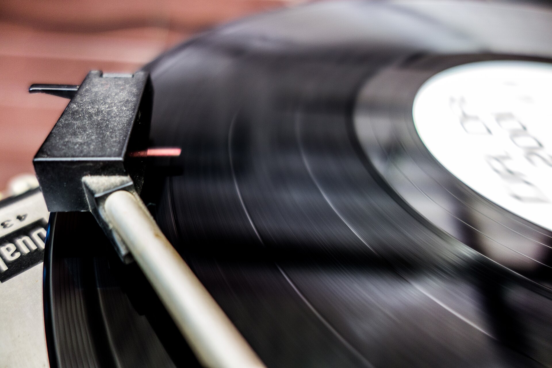 A turntable tonearm riding a black vinyl record