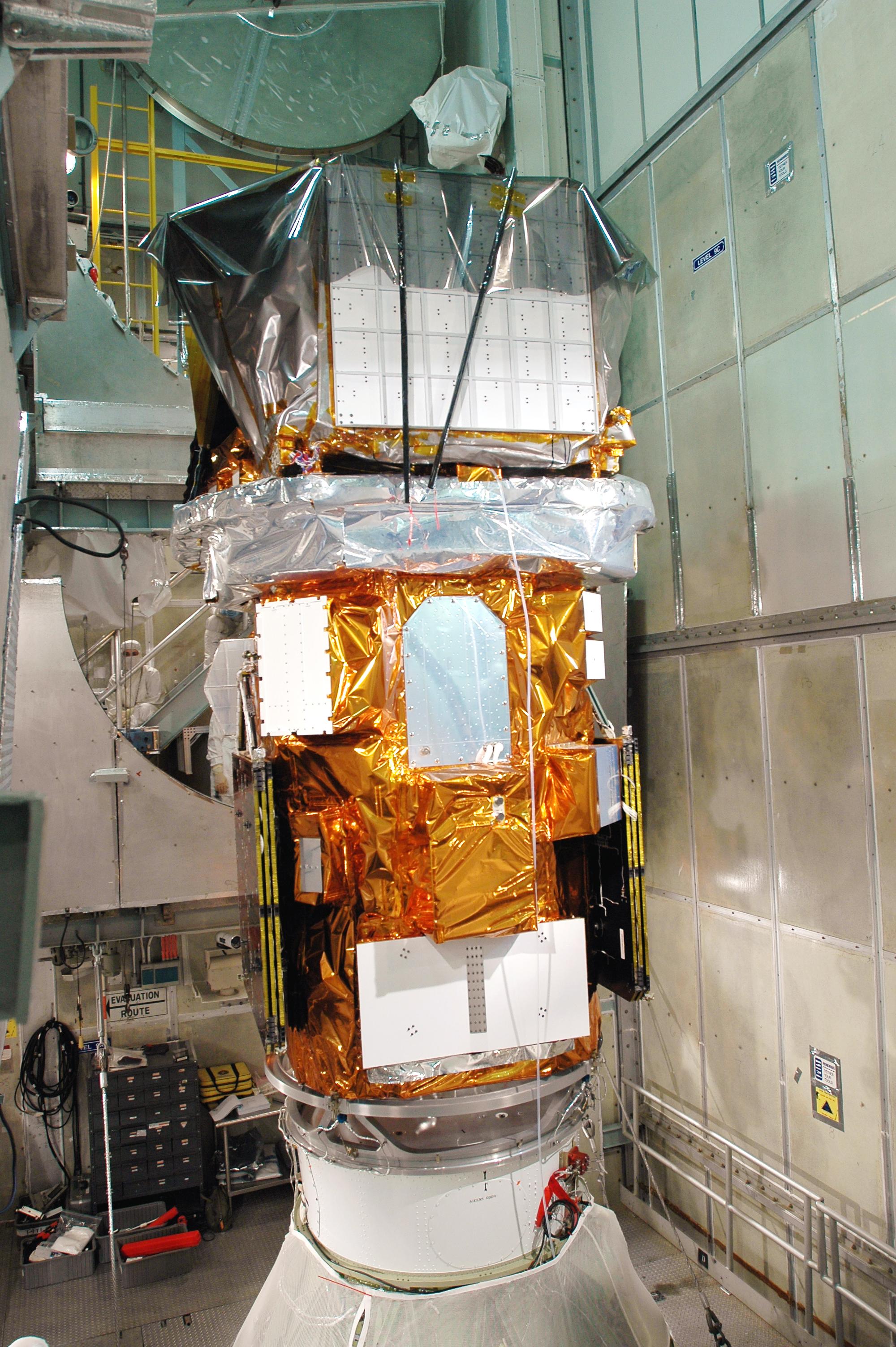 The Swift spacecraft, wrapped in gold foil and protective covers, mounted atop its Delta II rocket inside the mobile service tower at Launch Pad 17-A, Cape Canaveral, in November 2004