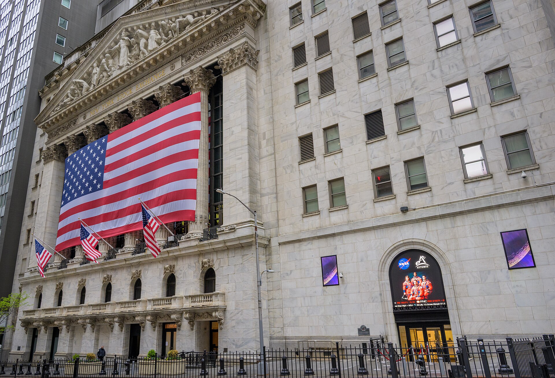 The facade of the New York Stock Exchange at 11 Wall Street, draped with large American flags in daylight