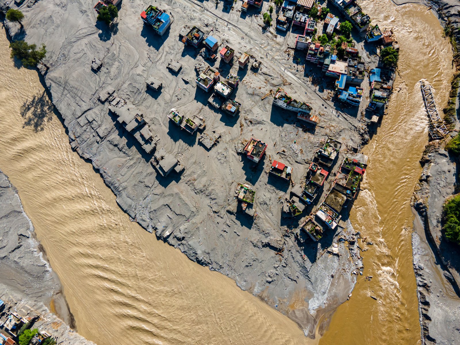 Aerial view of a Nepal village buried in mud with a destroyed bridge after the August 2026 floods