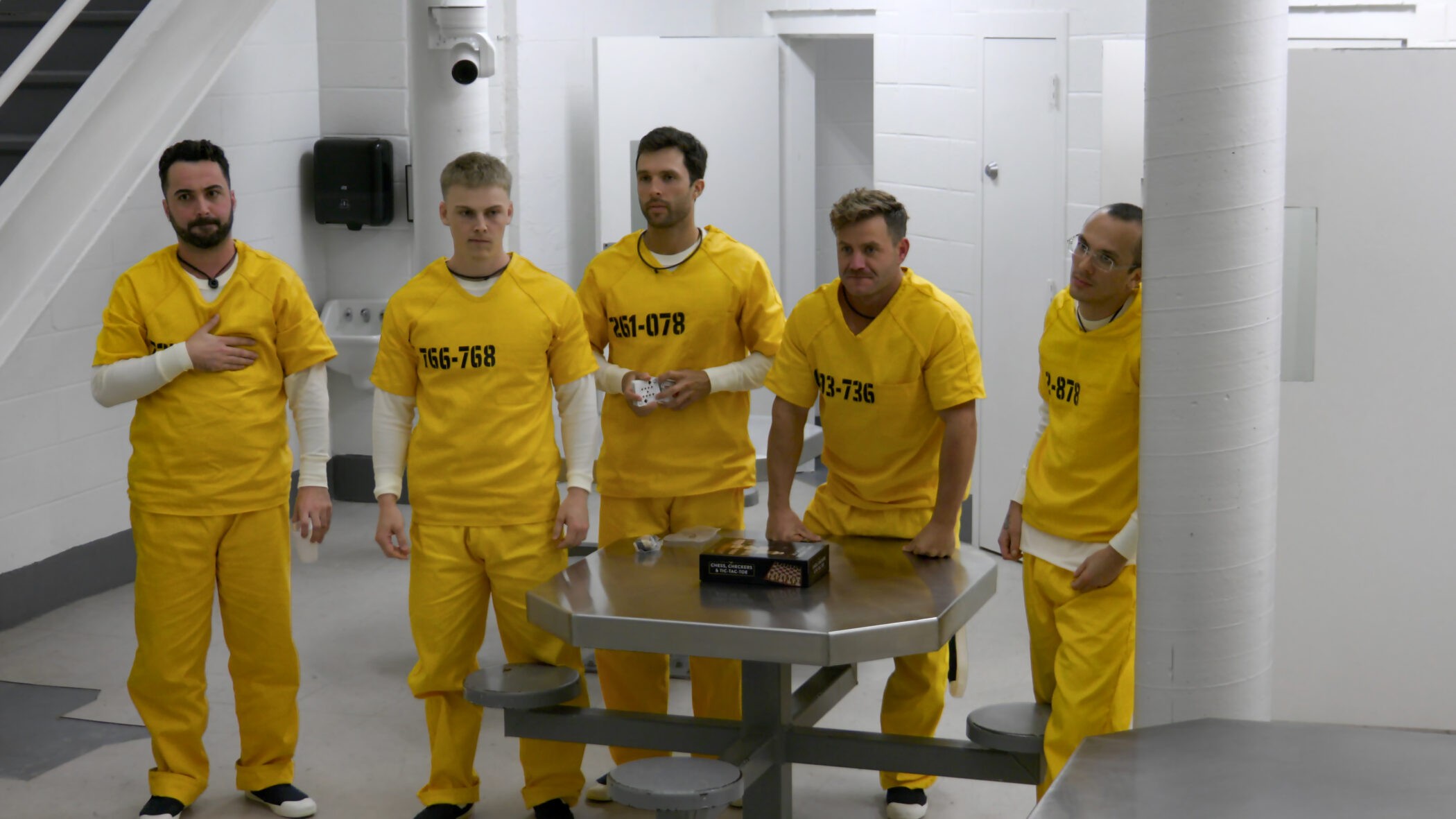 Five participants in yellow prisoner jumpsuits stand in the cell block in Netflix’s official publicity still for The New Stanford Prison Experiment
