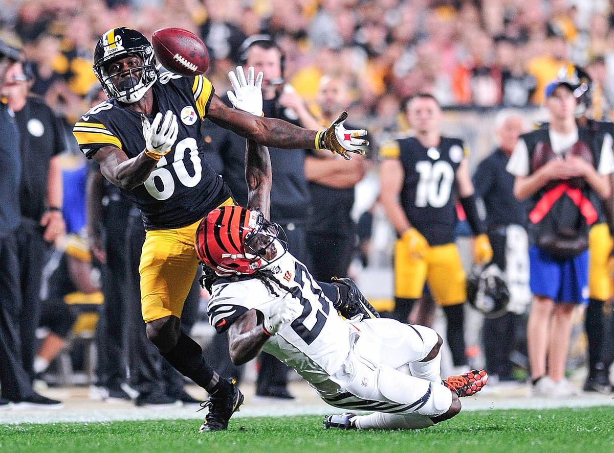 Steelers receiver stretches for a pass as a Bengals defender closes in