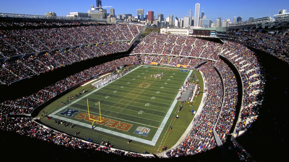 Soldier Field packed with fans on a sunny Chicago game day, with BEARS painted in the end zone.