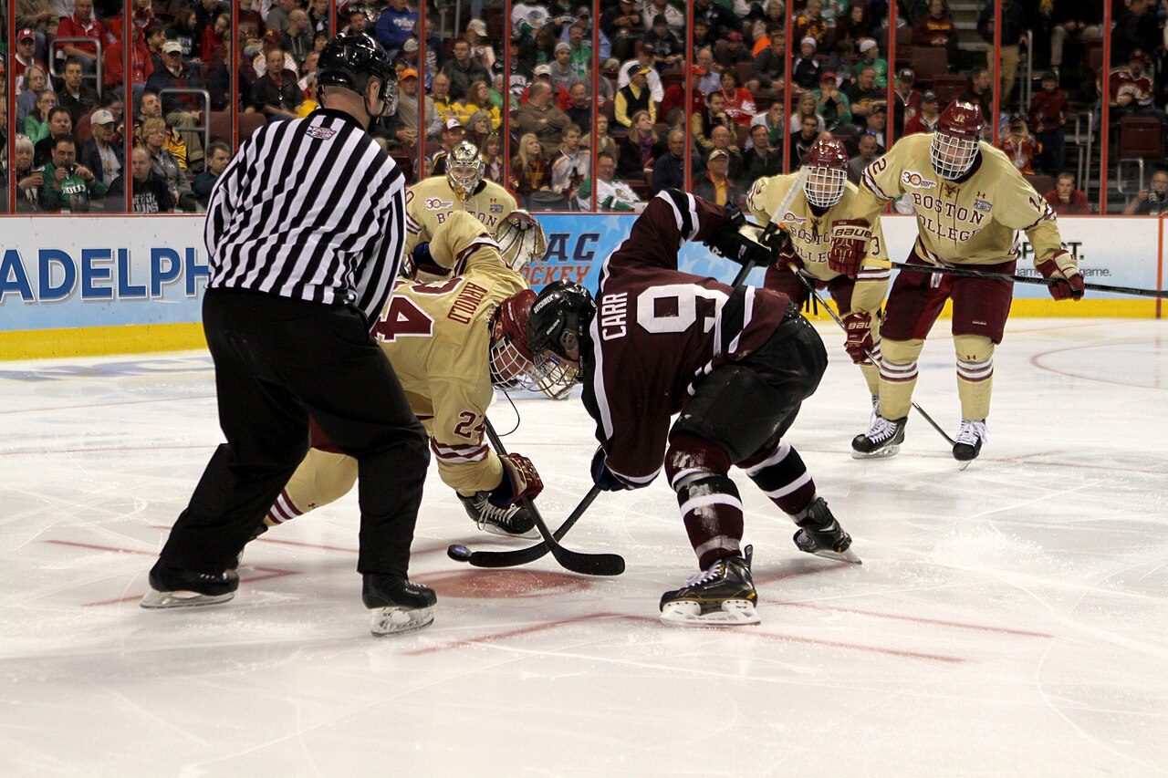 A hockey faceoff under bright arena lights.