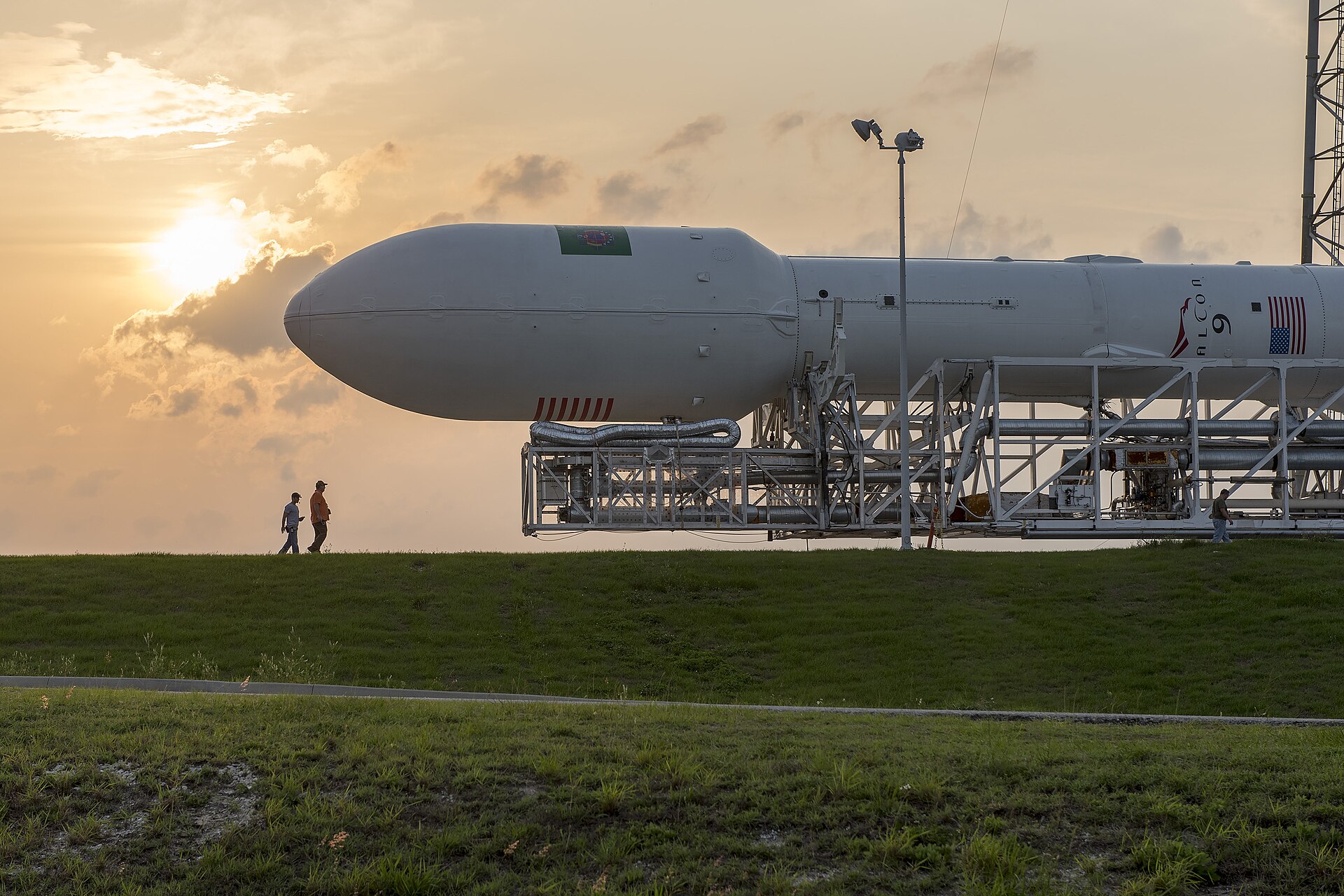 A SpaceX Falcon 9 rocket rolling out to the launch pad in bright daylight