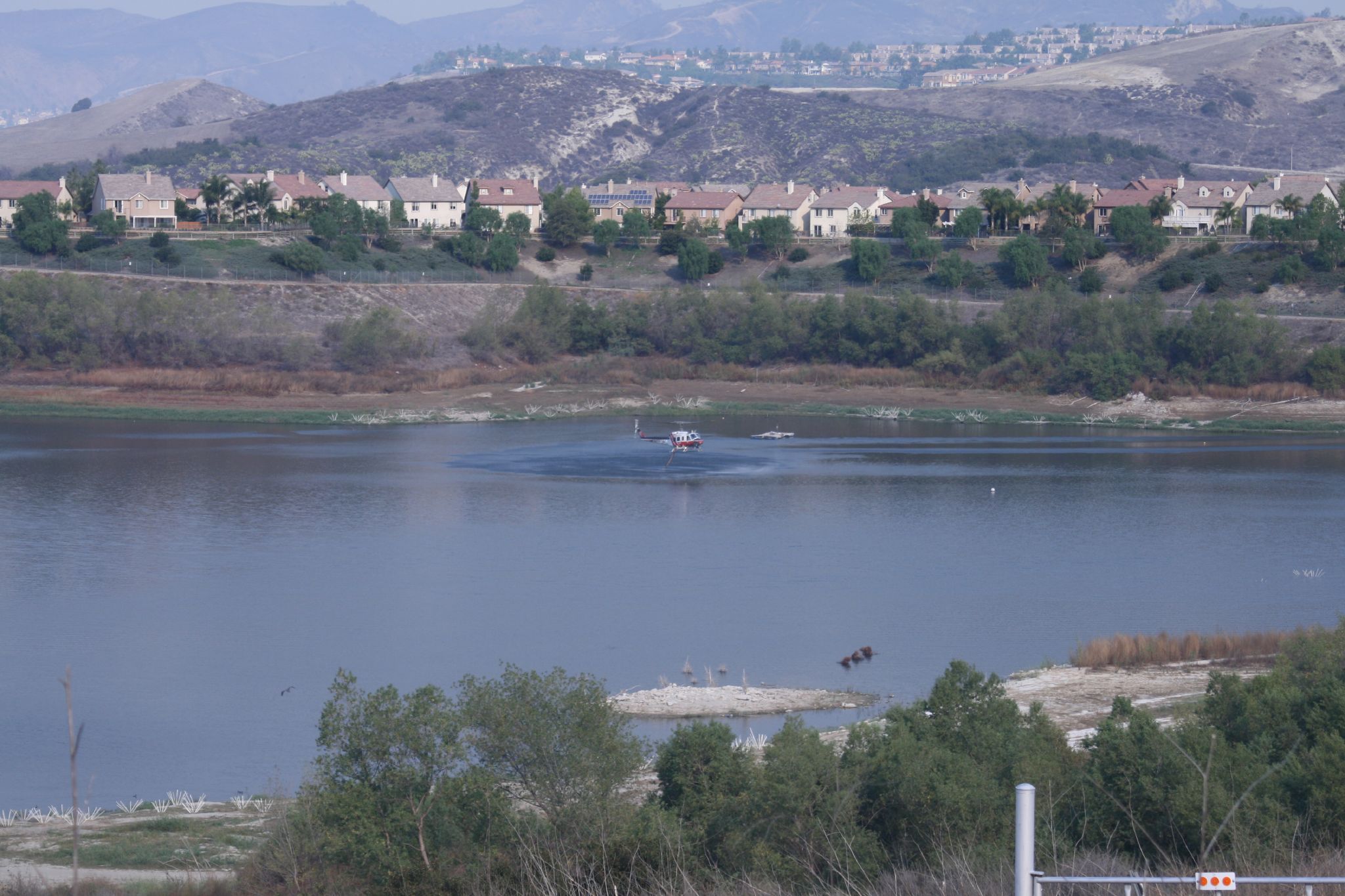 A firefighting helicopter makes a water drop over a brush fire in Orange County in daylight (file photo)