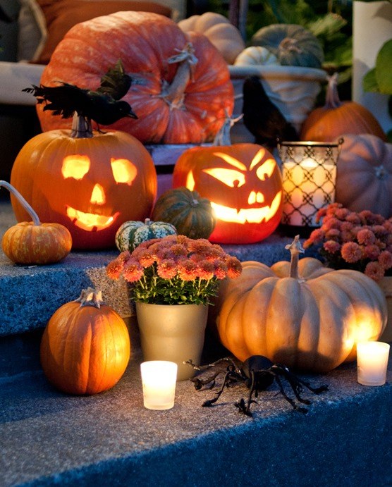 Jack-o'-lanterns and pumpkins glowing on a porch at dusk