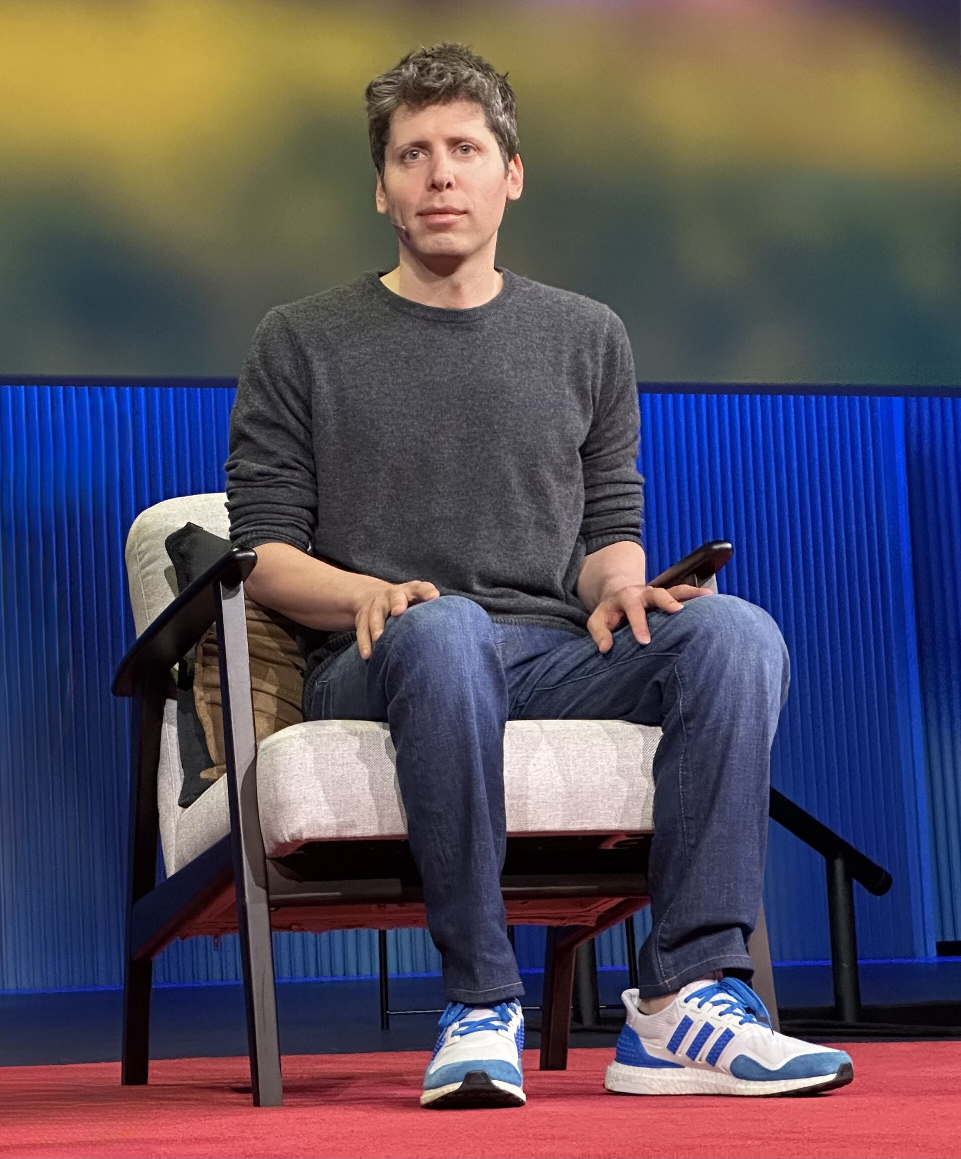 OpenAI CEO Sam Altman seated on stage during a TED talk.
