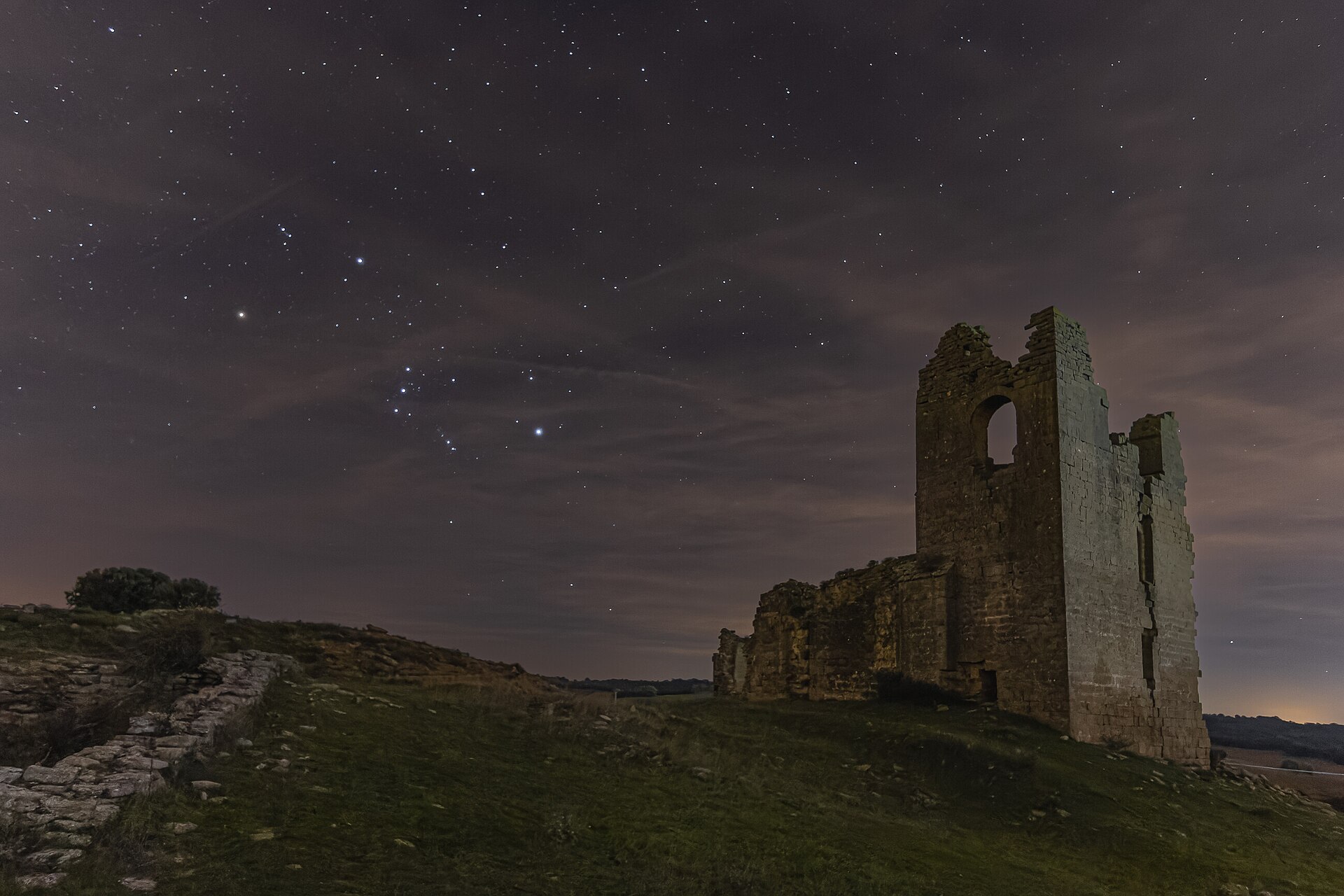 The constellation Orion over a ruined tower and hillside in Navarra, Spain