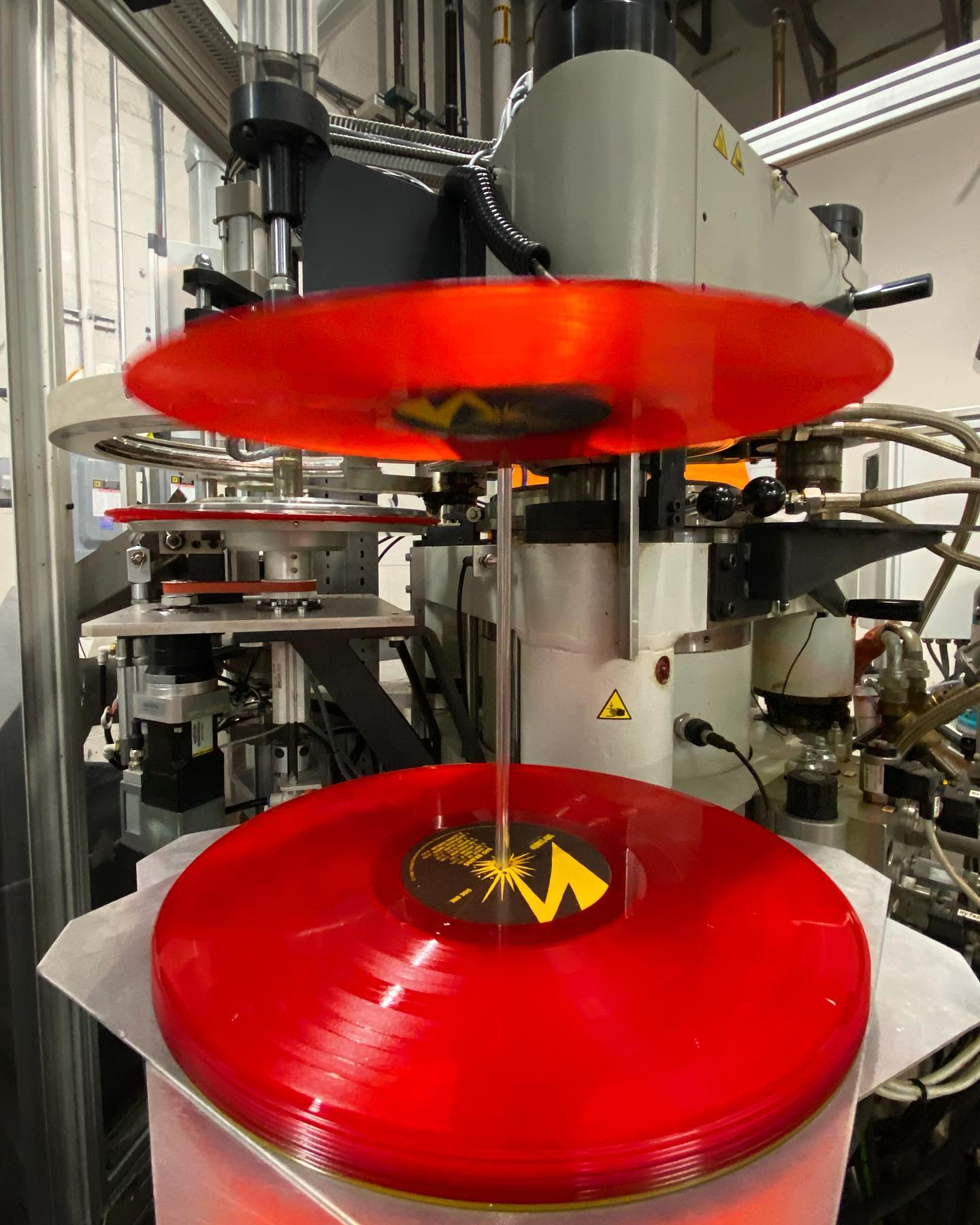 A red vinyl record being pressed at a record pressing plant
