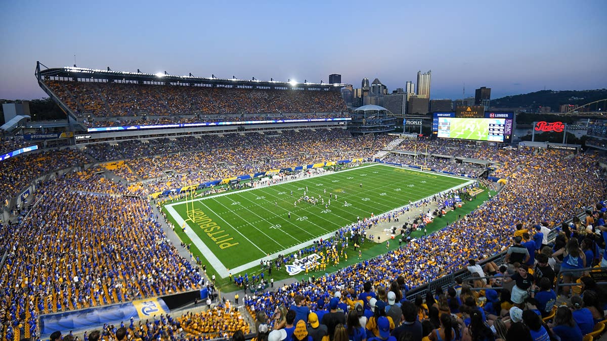 Acrisure Stadium at dusk, the Pitt Panther logo at midfield and a full blue-and-gold crowd