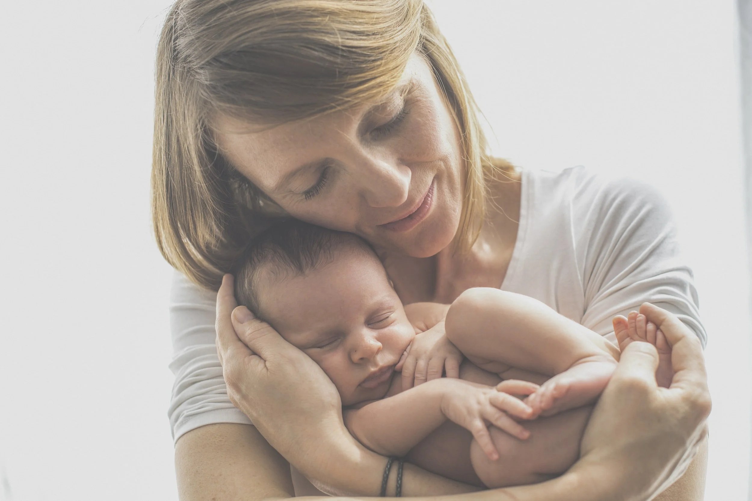 A new mother holding her newborn baby in bright natural light.