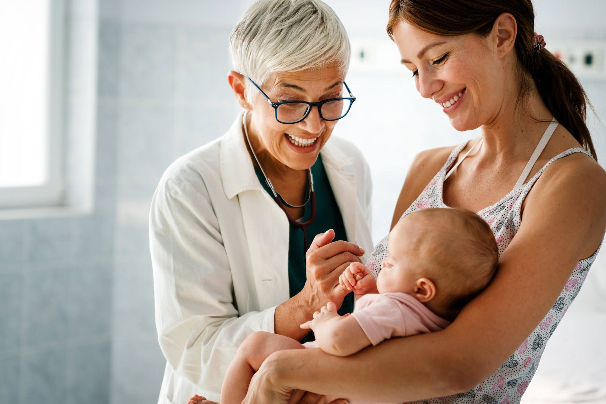 A doctor talking with a new mother holding her baby at a bright clinic visit
