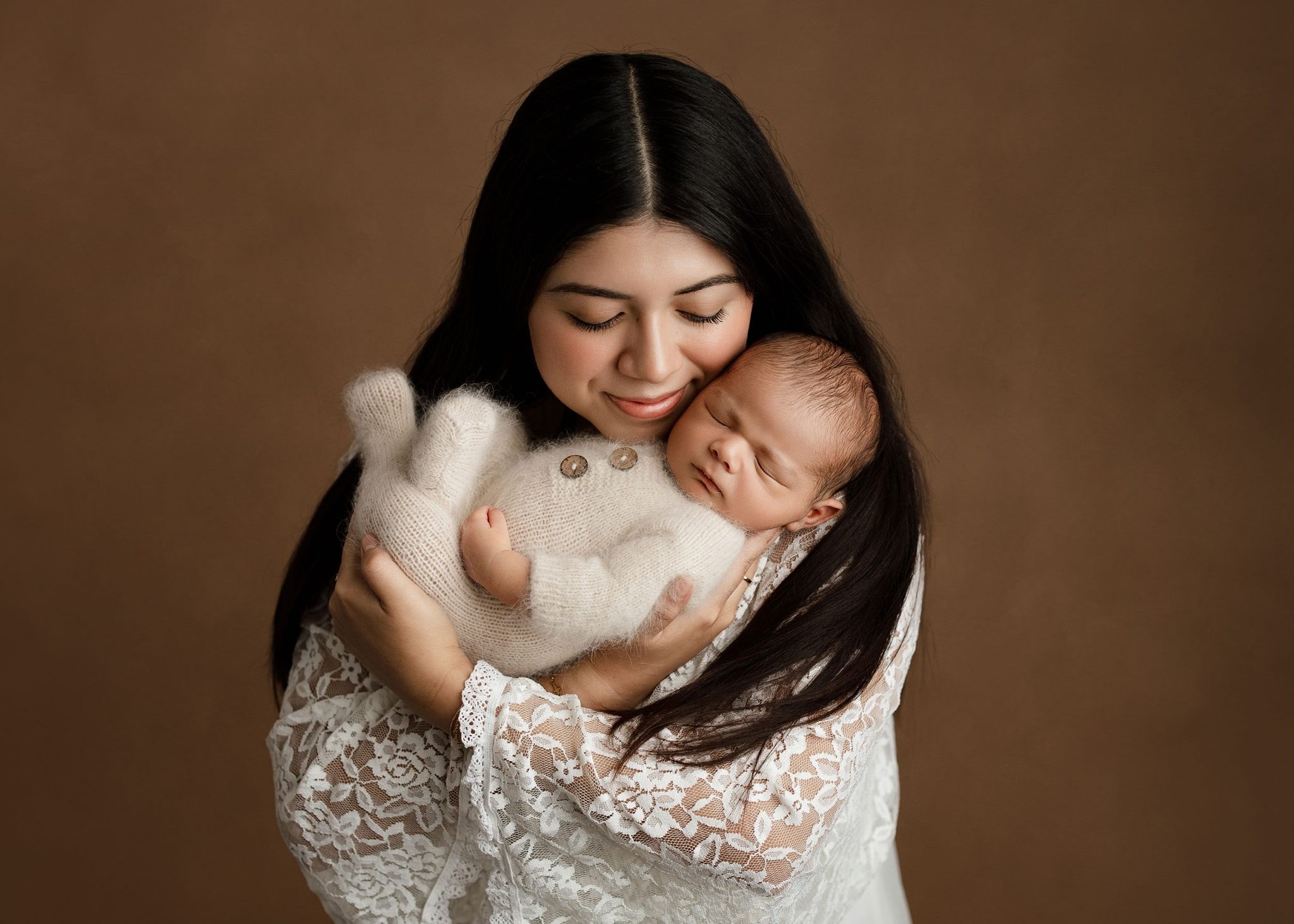 A smiling new mother holding her sleeping newborn baby