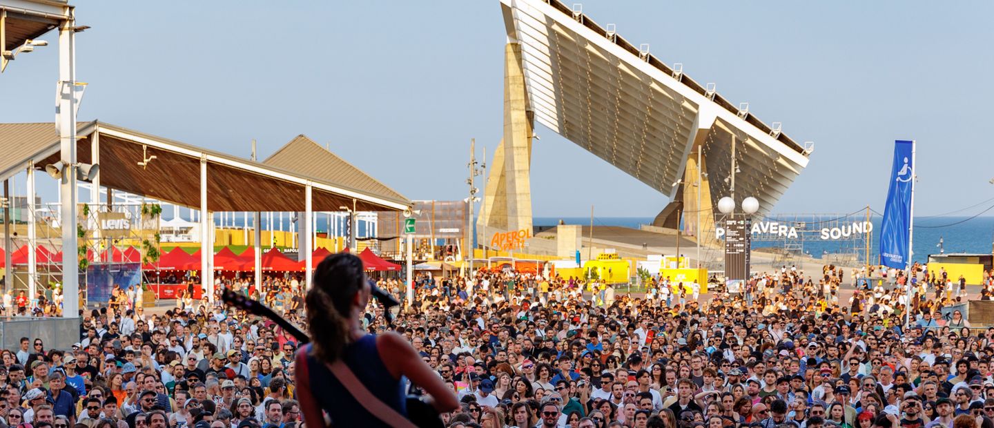 A performer on stage at Primavera Sound Barcelona before a large daylight crowd at Parc del Fòrum