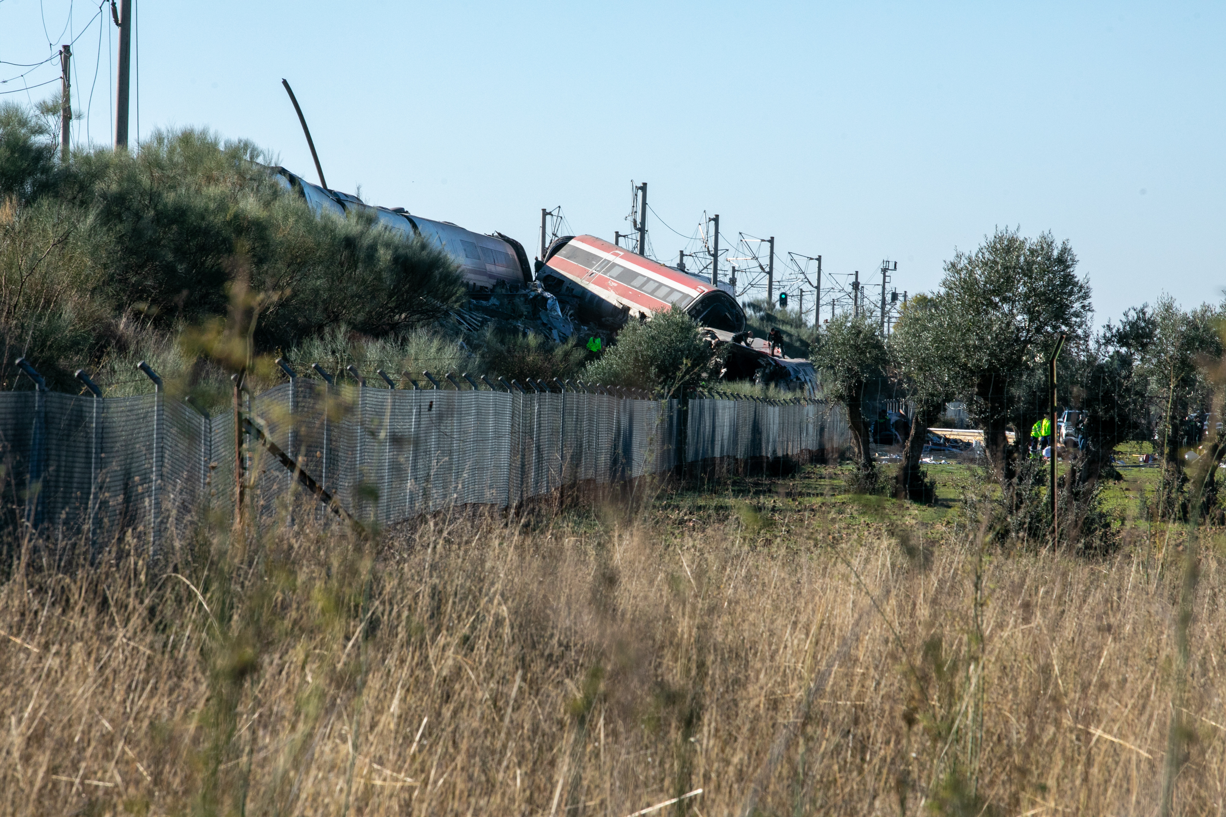 The scene of the collision between two high-speed trains near Urda, Spain — both derailed trains beside the Madrid–Seville line, surrounded by fire trucks, ambulances and responders across open fields
