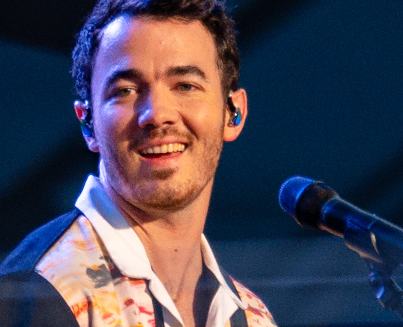 Kevin Jonas performing on stage with the Jonas Brothers in Cleveland in 2021, smiling at a microphone with his guitar — 2021 file photo
