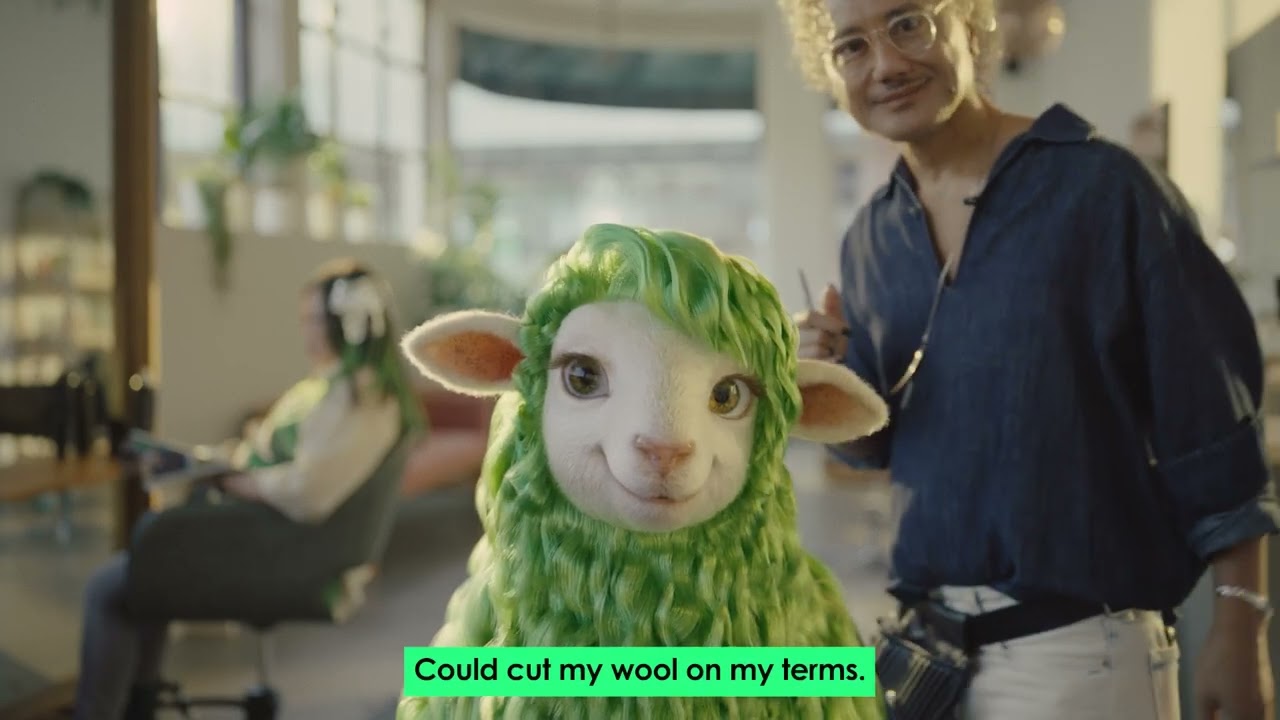 Buck, Kiwibank's green-wooled sheep mascot, at a hairdresser in the official Buck the System campaign film (video still)