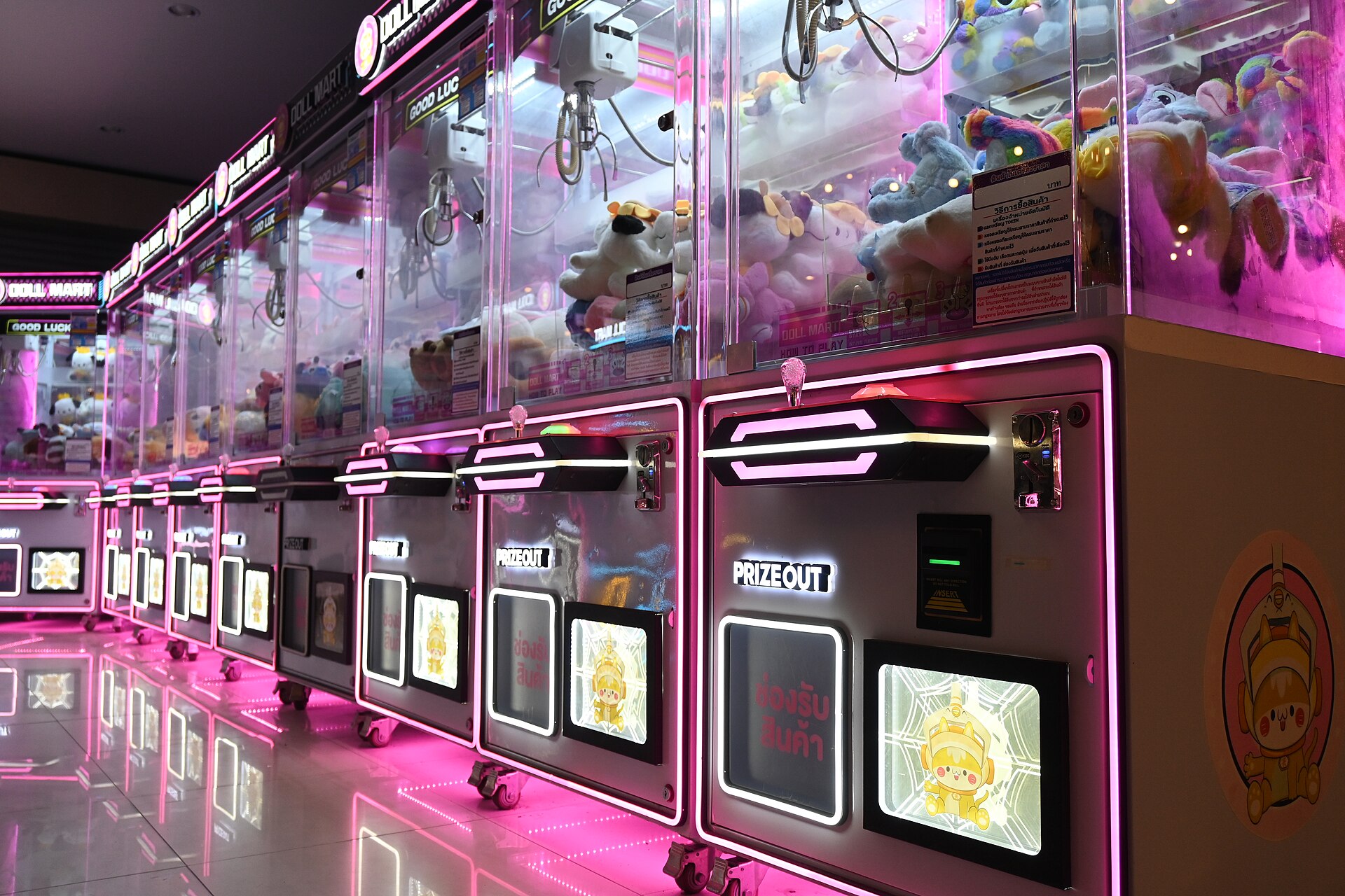 A row of brightly lit claw machines glowing in pink neon, filled with stuffed toys - file photo