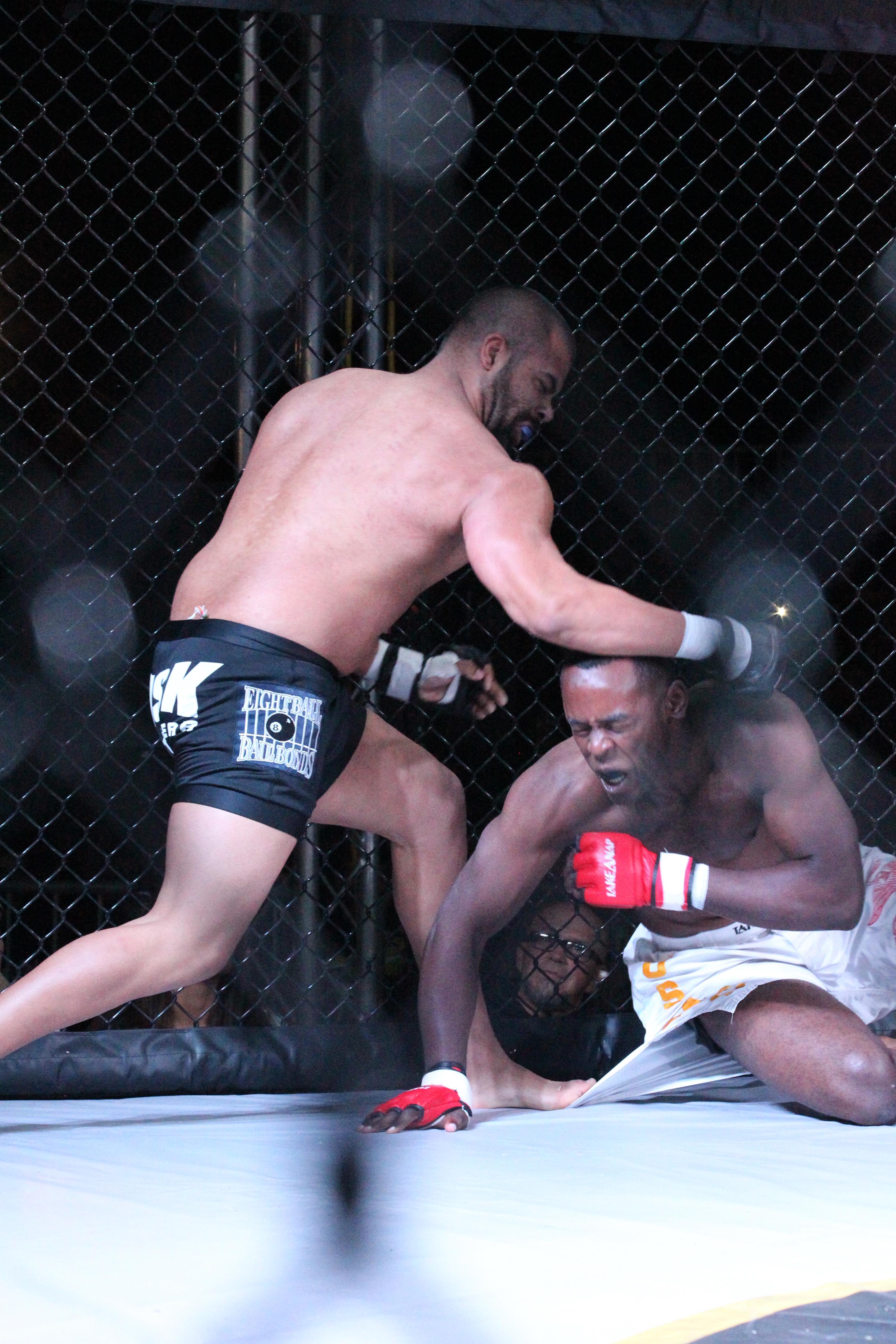 Two fighters battle against the cage in an MMA bout — file photo