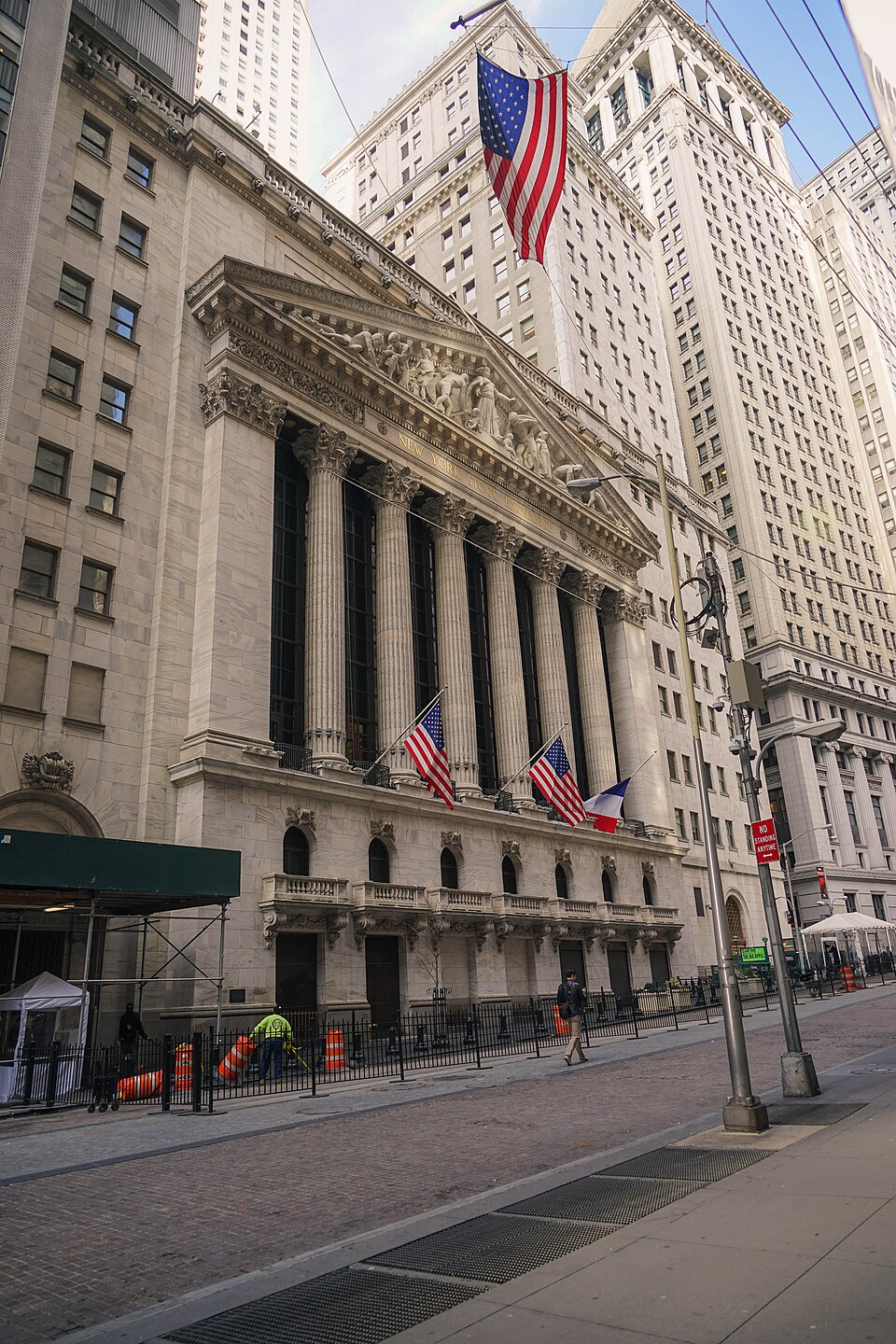 The columned facade of the New York Stock Exchange on Wall Street, American flags flying out front