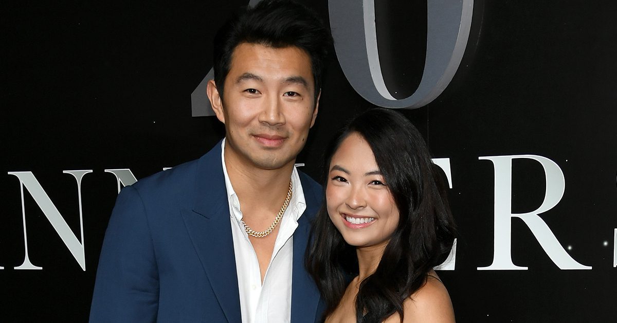 Simu Liu and Allison Hsu smile for photographers at a premiere.
