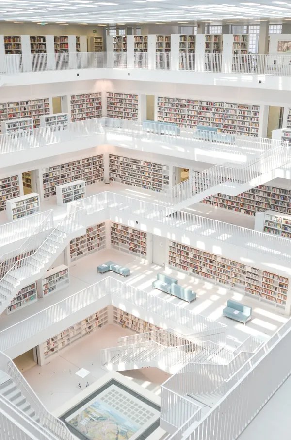 A bright modern public library interior, rows of shelves full of books