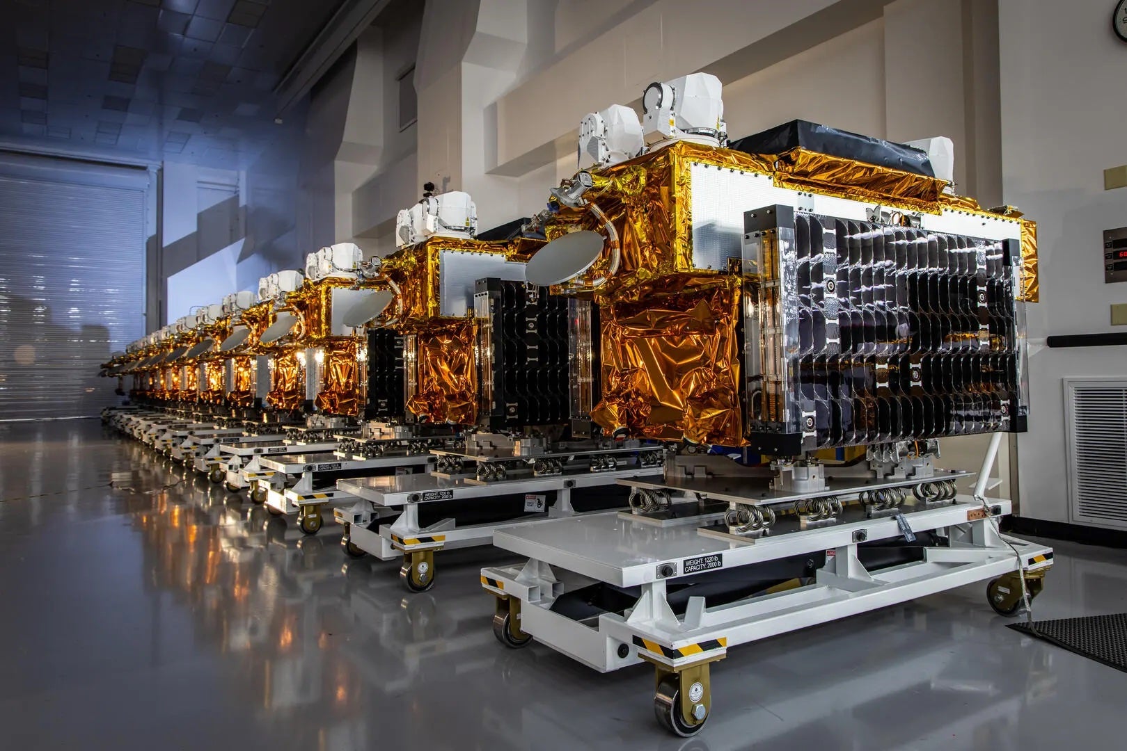 Tranche 1 transport-layer satellites lined up in a clean room ahead of delivery to Vandenberg