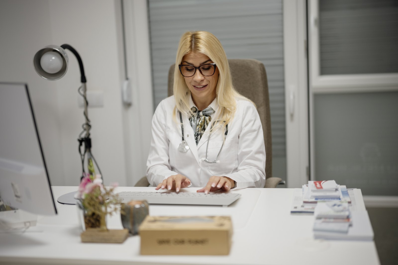 A doctor works at her desk in a bright medical office