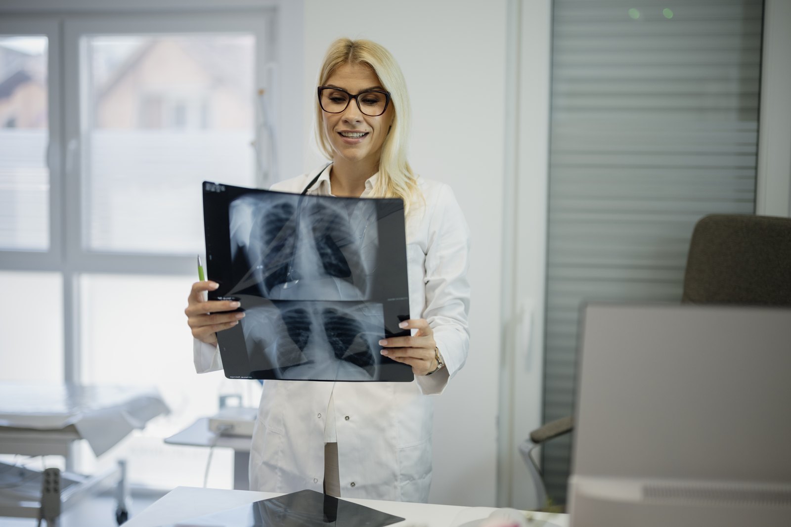 A clinician holds up chest X-rays in a bright clinic