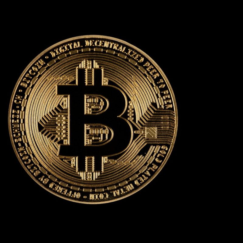 A physical bitcoin token on a black background