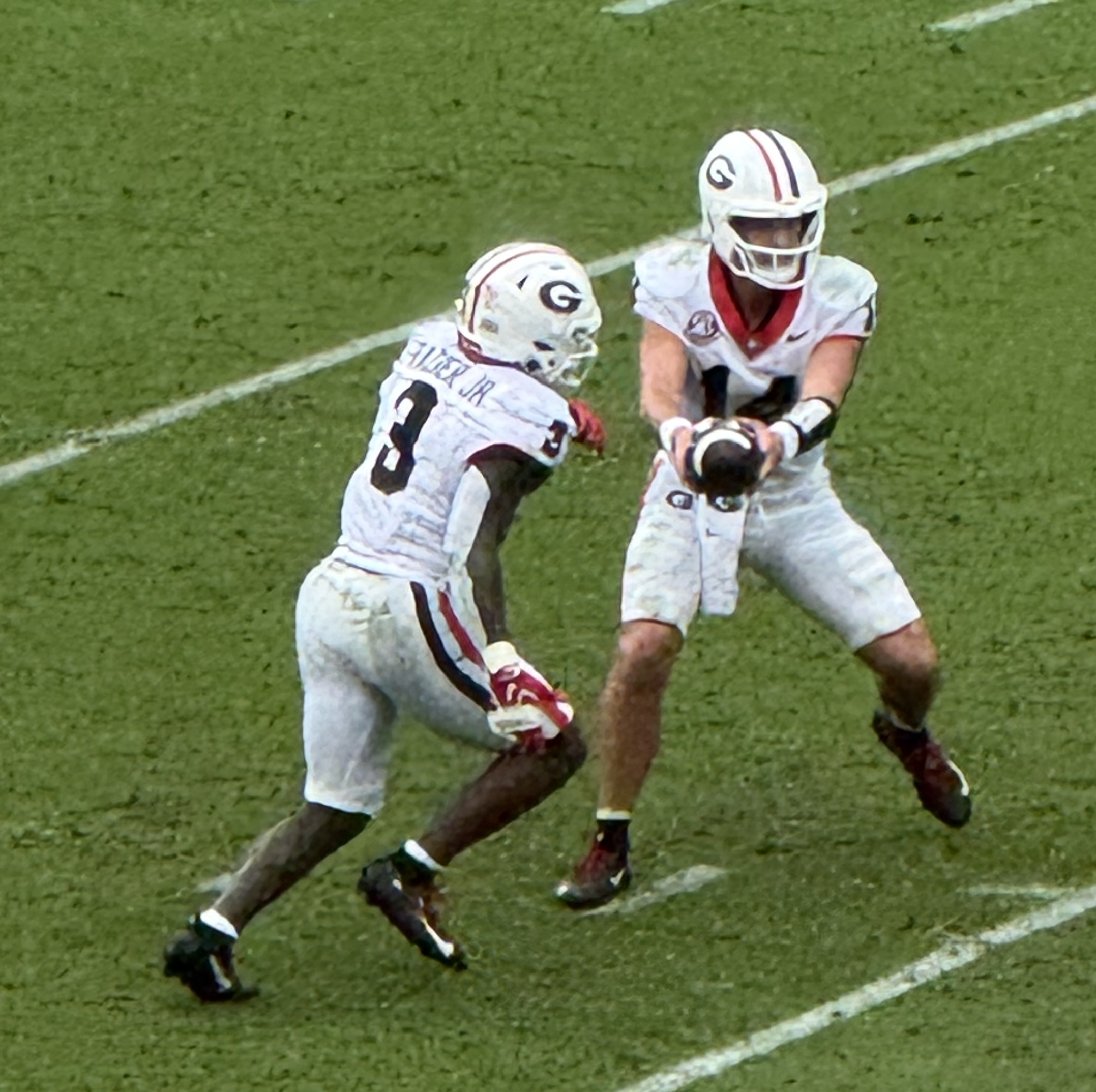 Gunner Stockton hands the ball off to Nate Frazier during a Georgia game, both in white away uniforms